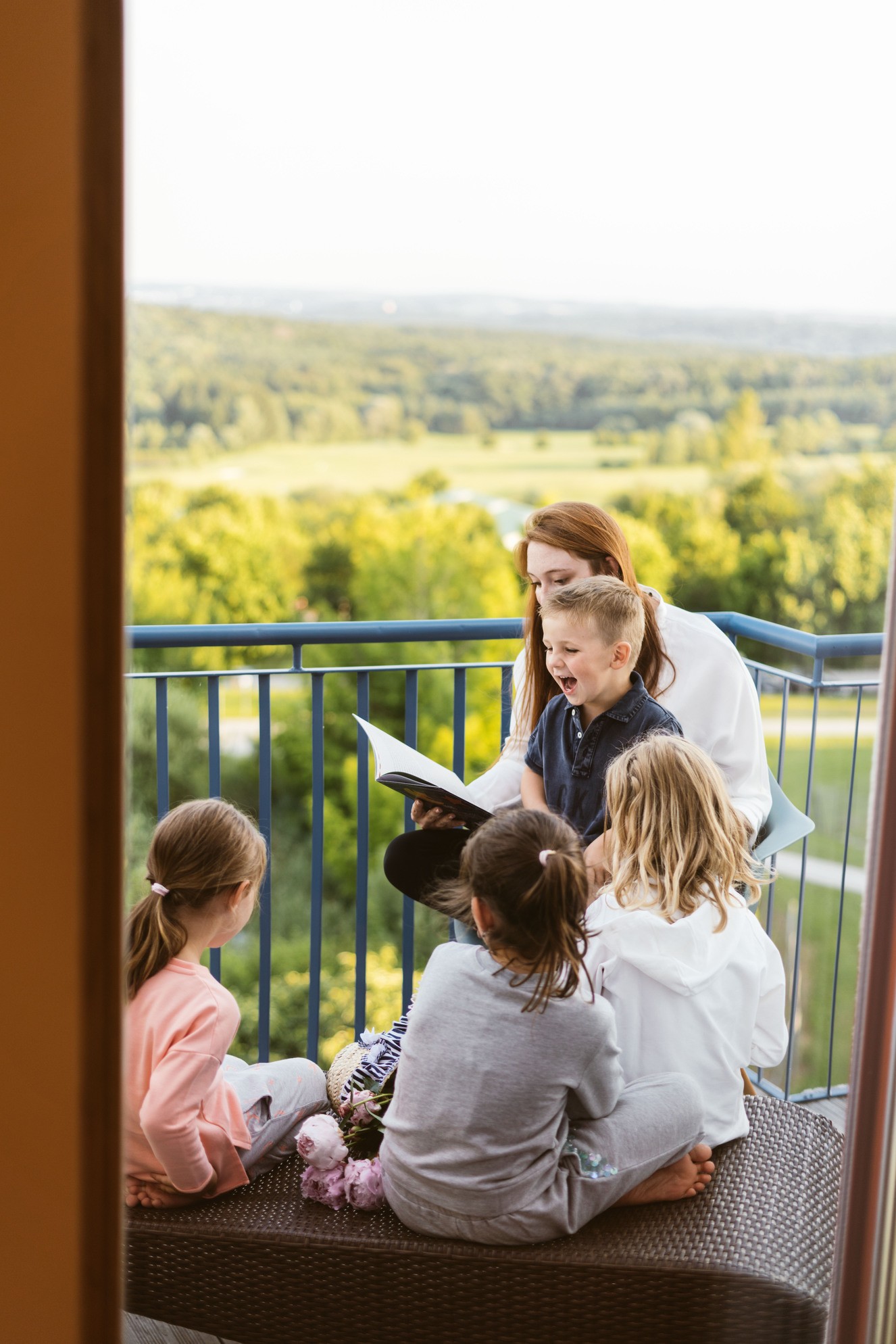 Hotel Reiters Finest Family - Frau liest Kindern am Balkon eine Geschichte vor