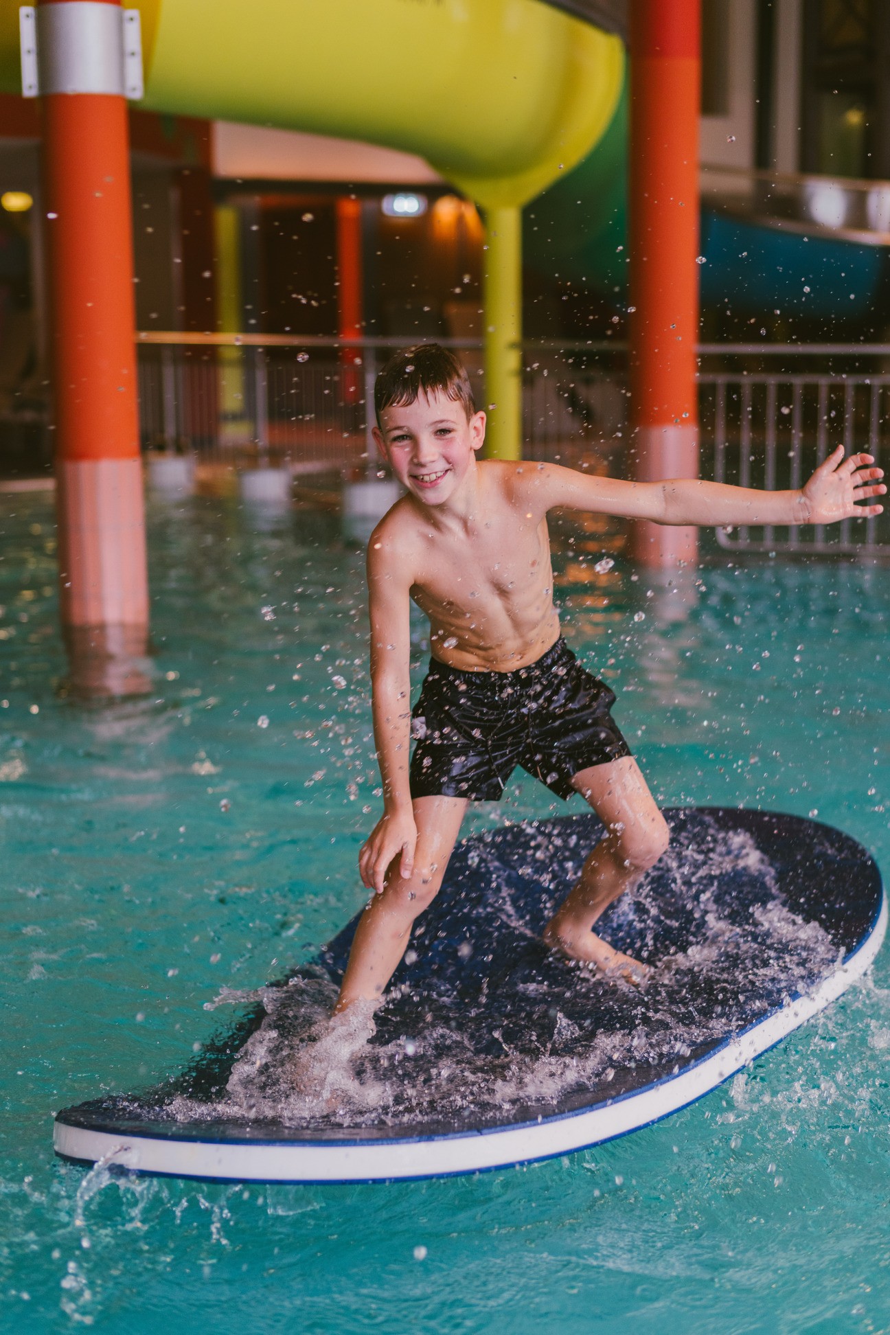 Hotel Reiters Finest Family - Junge steht auf Surfbrett im Pool