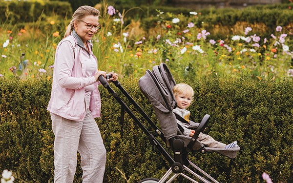Hotel Reiters Finest Family - Oma spaziert mit Baby im Kinderwagen durch die Blumenwiese