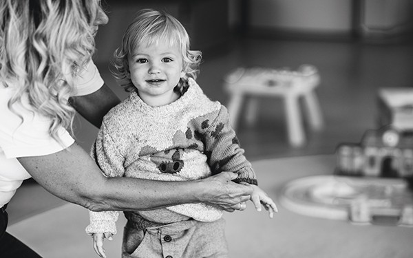 Hotel Reiters Finest Family - Baby lächelt in die Kamera und wird von Betreuerin gehalten